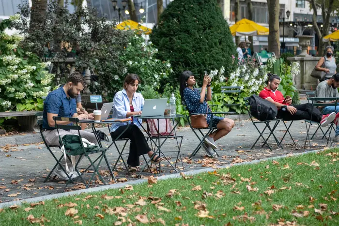 People sit on their laptops and phones in Manhattan's Bryant Park on August 18, 2021.